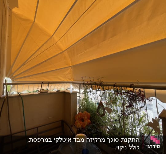 סוכך כתום נפרש מעל מרפסת עם צמחים